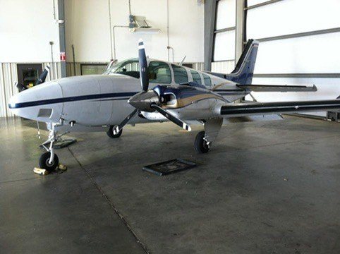 A Beechcraft Baron twin-engine airplane parked in a hangar.