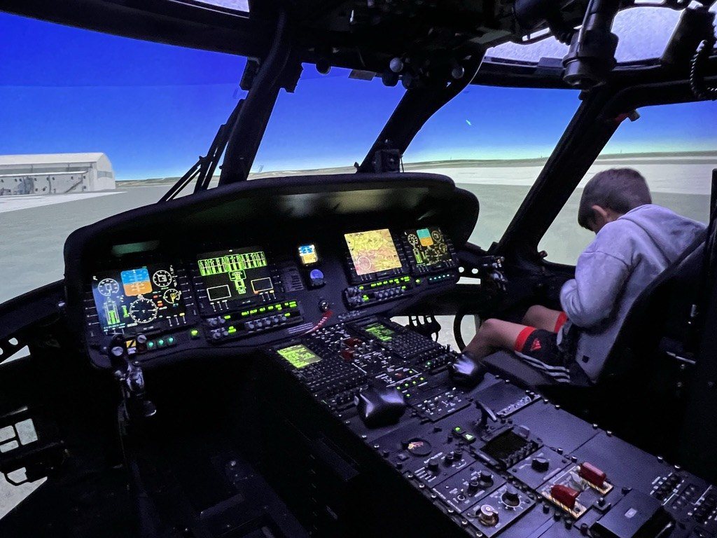 Our son Blake sitting in the cockpit of a helicopter flight simulator.