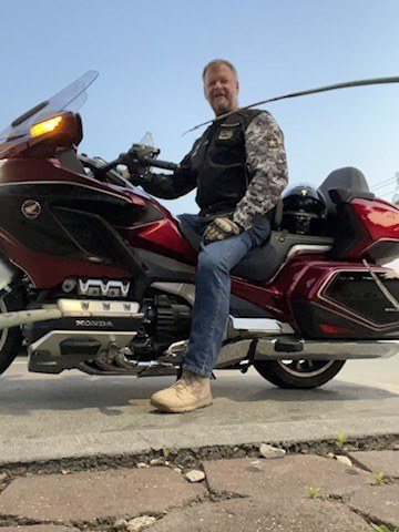 Glenn Wegner sitting on his red Honda Gold Wing motorcycle.